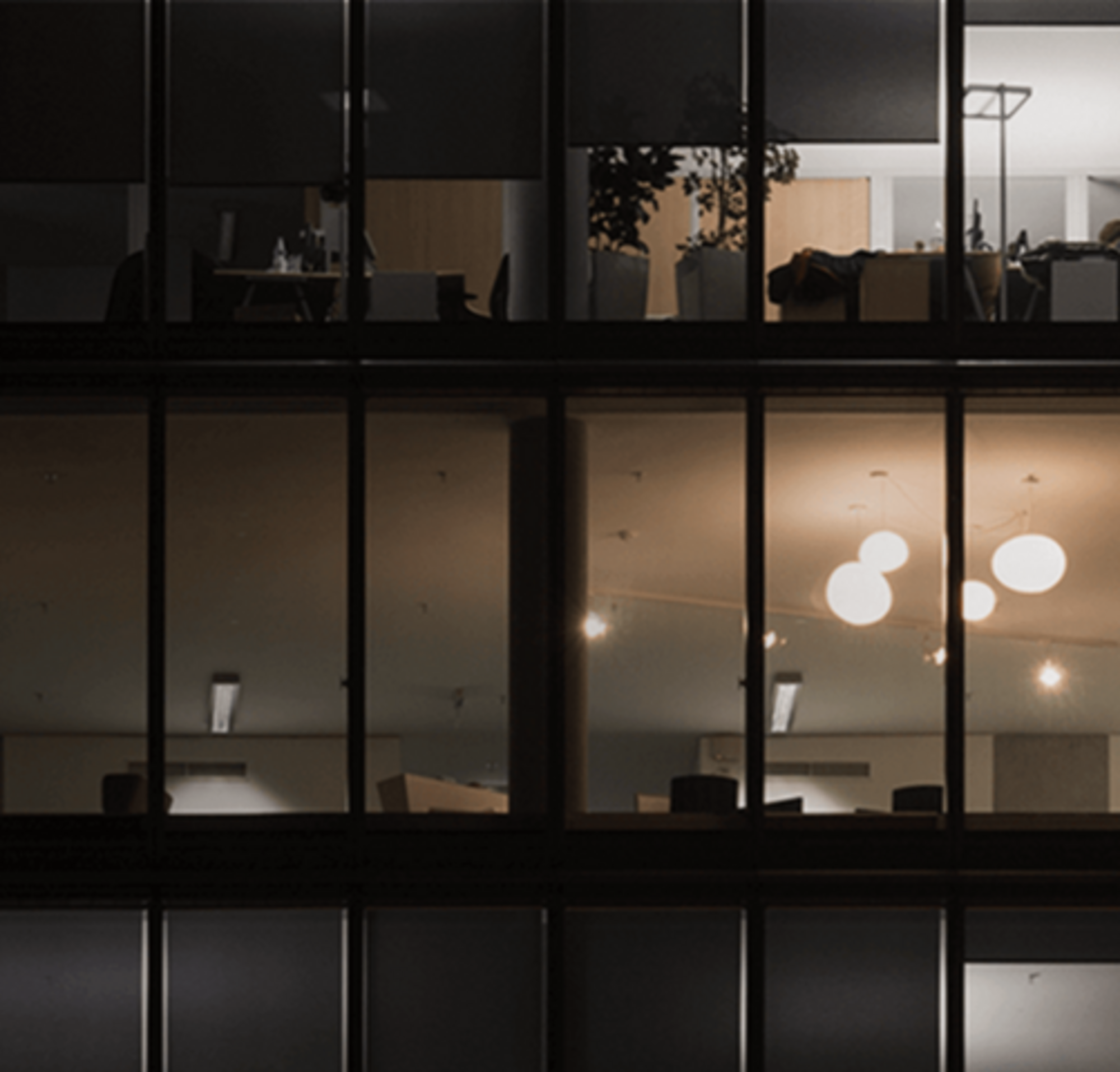 Ein Bild von drei größtenteils dunklen Stockwerken in einem mehrgeschossigen Bürogebäude bei Nacht.